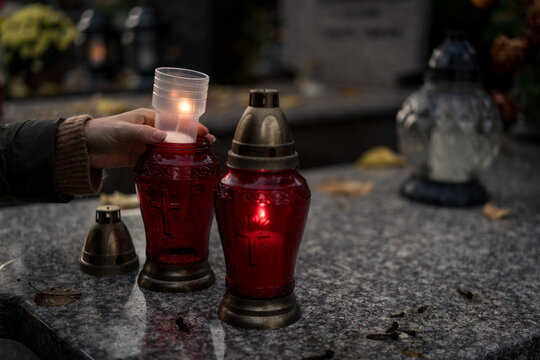 Hand lighting and placing a grave candle at a tombstone, close-up, Poland, November 1 - All Saints' Day (also known as All Souls' Day, Day of the Dead)