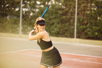Young beautiful woman playing a tennis match. Sportswoman having fun playing a tennis game with friends.