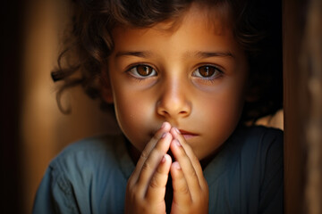 Portrait of a little girl praying in the dark.  - obrazy, fototapety, plakaty