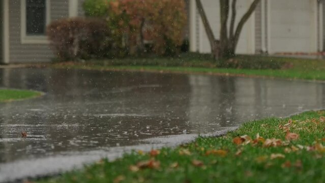 Slow Motion footage, heavy rain water drops falling into big puddle on asphalt, flooding the street.