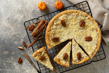 Thanksgiving dessert. Fall traditional pie pumpkin with crumble and pecan on a gray stone background. View from above. Copy space.