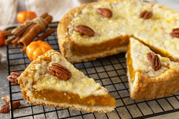 Thanksgiving dessert. Fall traditional pie pumpkin with crumble and pecan on a gray stone background.