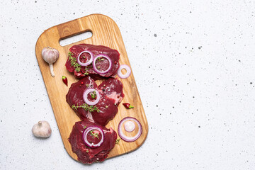 Raw beef steaks fillet mignon on the wooden board with herbs and spices on white stone background...
