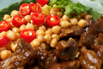 beef meat fried in a frying pan with chickpeas and chili peppers close-up, top view