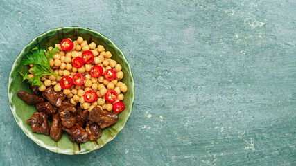 beef meat fried in a frying pan with chickpeas and chili peppers close-up, top view