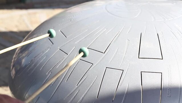 Glucophone instrument and sticks for playing music. Playing a glucophone on a metal tongue drum with the help of special sticks.Drum for meditation and mental health.