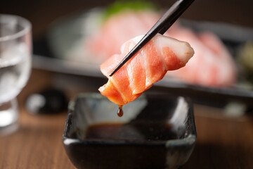dipping blue fin fatty tuna slice into soy sauce
