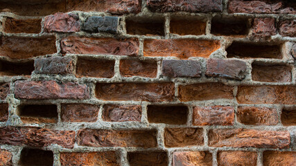 Old eroded brickwork with knocked out bricks. Erosion of an old faded red brick wall