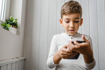 One caucasian boy child use smartphone mobile phone at home play games