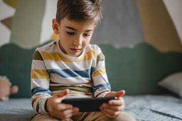 One caucasian boy child use smartphone mobile phone at home play games
