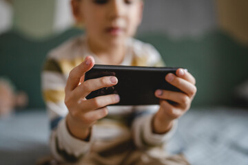 One caucasian boy child use smartphone mobile phone at home play games