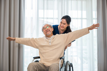 Happy curator person doctor pushing and walk elderly patient freedom raising arm at hospital, Asian senior retired old man sitting on wheelchair having fun with young woman nurse, disabled sanatorium - obrazy, fototapety, plakaty