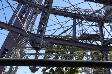 Metal steel construction background. Beams and handrail details. Blue sky and green tree on the back