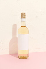 Wine bottle with blank label. White wine on pink background with copy space