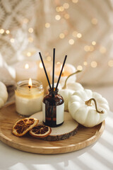 Still life details in the living room. Autumn composition with aroma diffuser with pumpkin pie scent, knitted sweaters, burning candles. Concept of slow life, relaxation, detention. Apartment decor