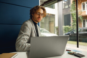 Focused businessman in eyeglasses working on laptop sitting in office during working day