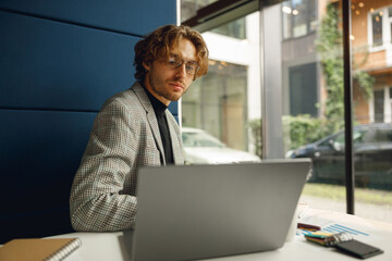 Fototapeta premium Focused businessman in eyeglasses working on laptop sitting in office during working day