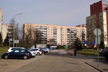 A housing estate with blocks of flats built in the 1980s by the access road with parked cars in Poland