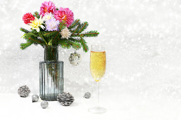 Christmas creative bouquet of live fir branches in a vase, with chrysanthemum flowers, decorations and a glass of champagne on an elegant festive background. Christmas and New Year mockup for design 