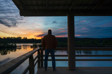 Fototapeta premium Man looking at the lake and the sunrise