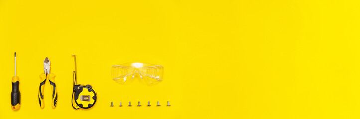Set of tools, screwdriver, cutting pliers, tape measure, protective glasses and screws on yellow background, banner, flat lay. - obrazy, fototapety, plakaty
