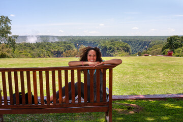 Victoria Falls in Zimbabwe,  holiday woman on siting on a wooden bench, behind the train passing on...