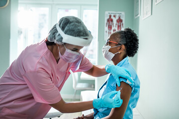 Senior female patient getting vaccinated by a health worker at the hospital