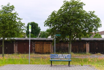 A plain bus stop in Luebbenau, Germany with a bench colored with graffiti and a sign