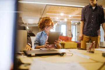 Fototapeta premium Young Caucasian woman using a tablet in the office of a startup company