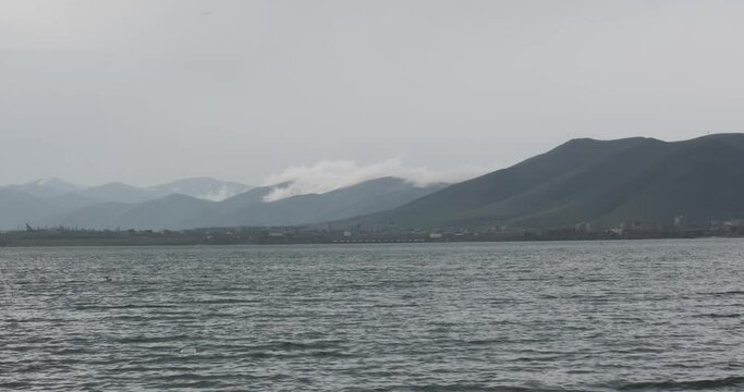 Amidst the Armenian highlands, Lake Sevan stands as a testament to nature's beauty. On this particular day, the descending clouds create a mesmerizing interplay of light and shadow on the water, with