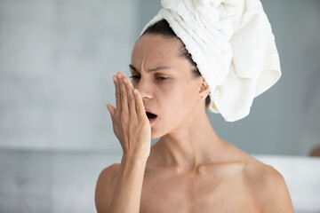 Young woman wrapped in towel after shower breathe in hand check freshness of breath in home...