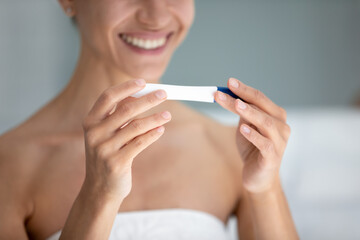 Close up of overjoyed young woman after shower do medical quick pregnancy ovulation test, get positive result, smiling female excited about future maternity confirmation, fertility, ivf concept