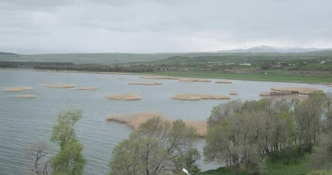Capture the breathtaking panorama from a great height, overlooking Lake Sevan with its reed-covered shores and majestic mountains in the distance.