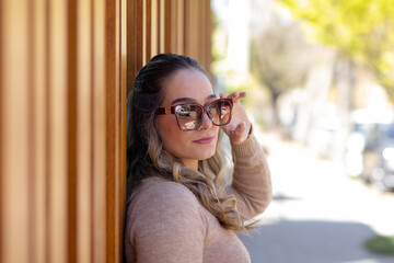 Portrait of young woman wearing modern sunglasses on wooden wall background. Spring, summer style. Fashion concept. Optics, glasses.