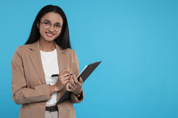 Beautiful secretary with clipboard and pen on light blue background, space for text