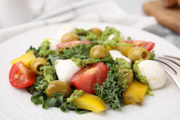 Delicious salad with pesto sauce on white plate, closeup