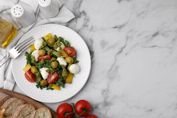 Delicious salad with pesto sauce, ingredients and fork on white marble table, flat lay. Space for text
