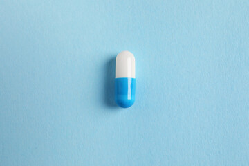 Fototapeta na wymiar One colorful pill on light blue background, top view
