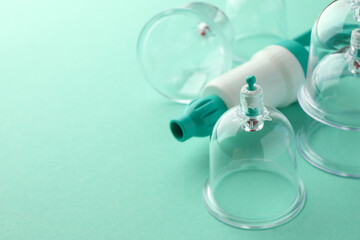 Plastic cups and hand pump on turquoise background, closeup with space for text. Cupping therapy