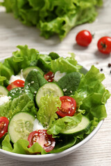 Delicious salad in bowl on white wooden table, closeup