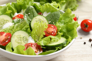 Delicious salad in bowl on white wooden table, closeup