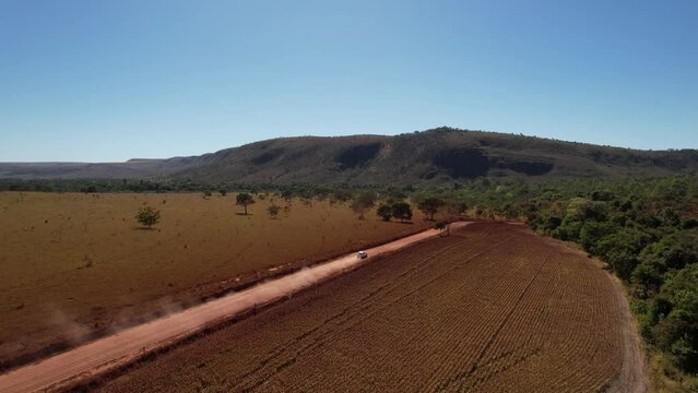 drone view of a moving car raising dust on a dirt road in Chapada dos Veadeiros, Goiás, Brazil