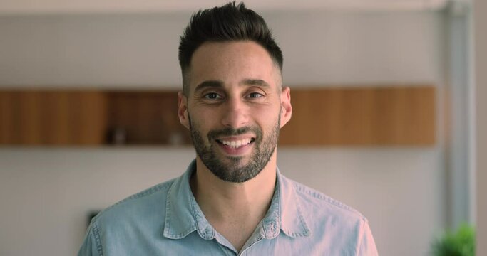 Cheerful Hispanic guy pose, staring at camera feel happy enjoy weekend at own or rented home. Head shot portrait man worker standing in office looks satisfied with career and professional achievement
