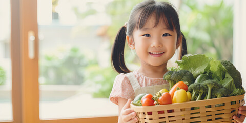 Cute asian child girl holding basket of vegetables prepare for cooking with her parent