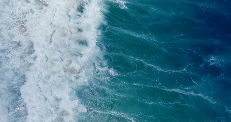 Slow motion sea wave Vitality of blue energy and clear ocean water. Powerful stormy sea waves in top-down drone shot perspective.  Crashing wave line in Andaman sea with foamy white texture.