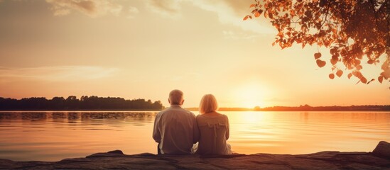 Elderly couple on lake shore enjoying sunset on romantic getaway With copyspace for text