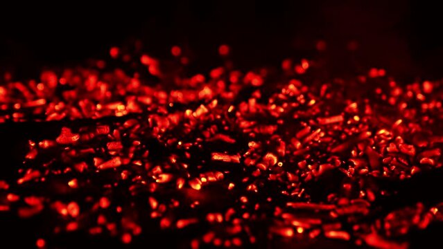 Pile of glowing charcoal after the campfire burnt out. Red pieces of burned wood still hot. Close up.