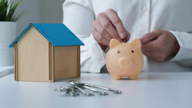 Woman putting coins into piggy bank. Savings for buy own home concept. Mortgage, loan, buying new home, real estate purchase and investment