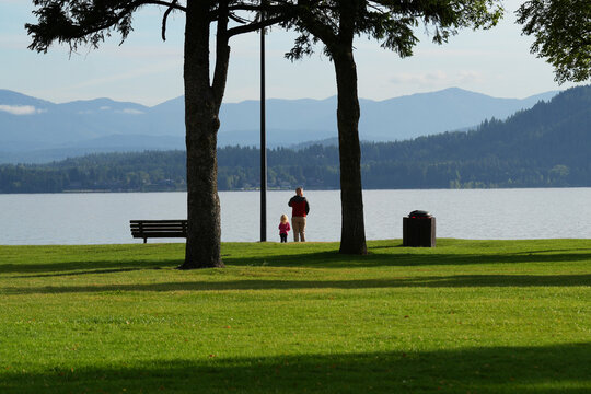 Father and daughter look across a lake at distant mountains