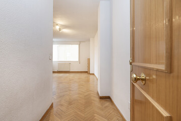 Home hall with armored white oak wood door with access to an empty living room with light oak flooring